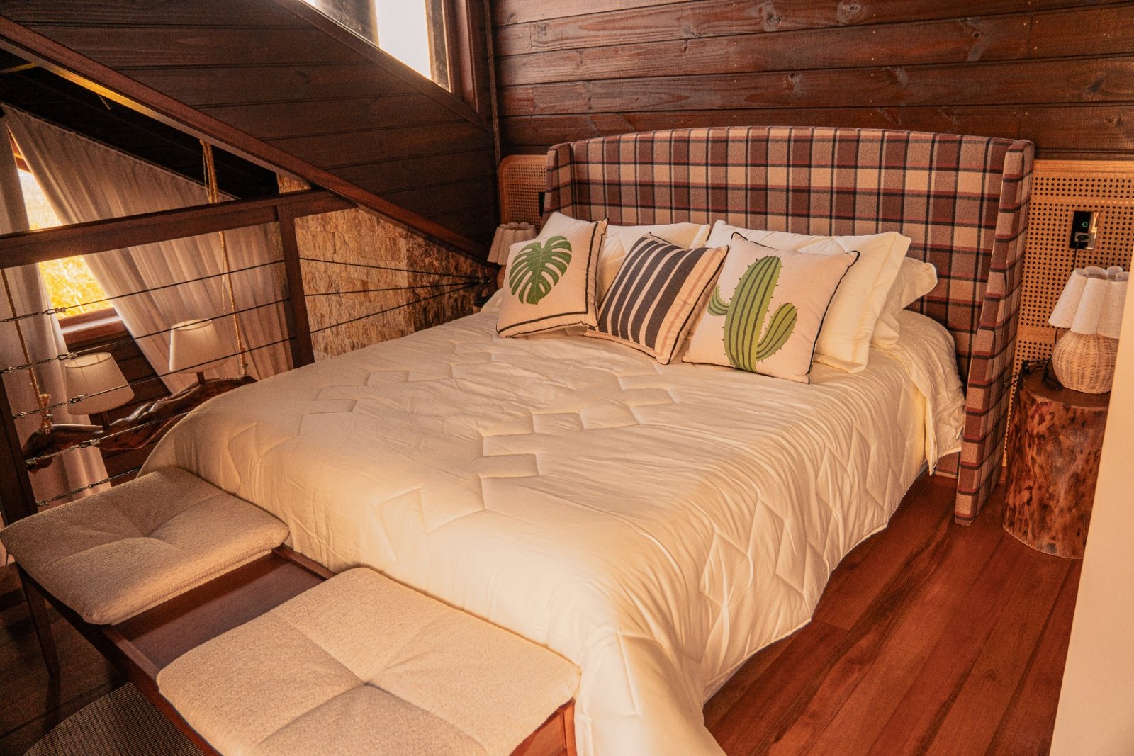 Quarto no mezanino com cama king, cabeceira em xadrez e detalhes em madeira